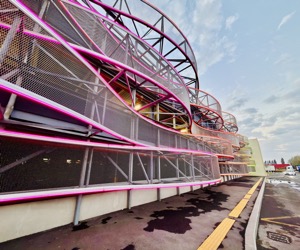 Neon trajectories animating a steel structure at dusk