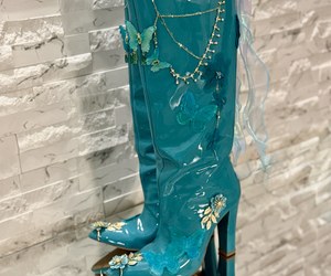 Élysée Papillon — Golden chains drape across the upper shafts above the long pointed toes and sculptural heels.